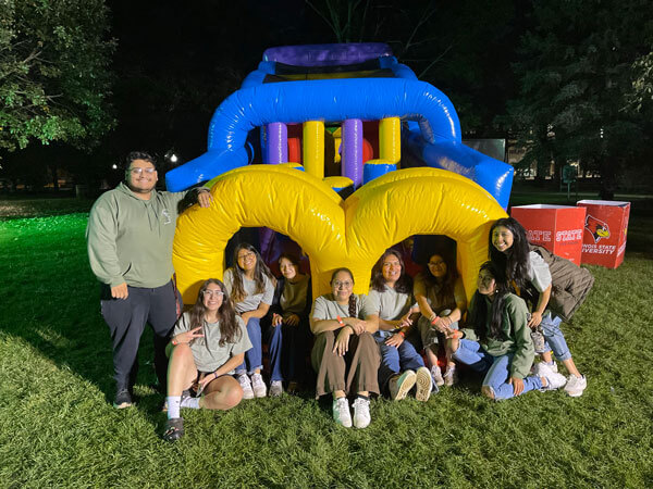 Students pose for a photo around a bounce house.