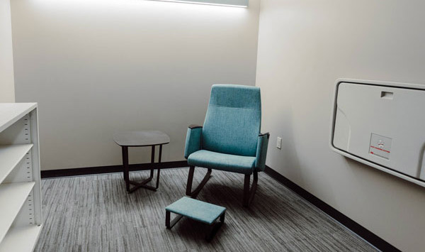 Alma V. Samuels Family Room with a chair, foot rest and a baby changing table mounted on the wall.