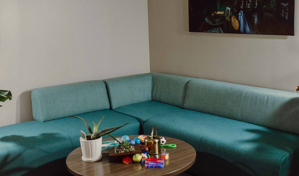 Green Room with large sectional sofa and coffee table with a plant and various object on top.